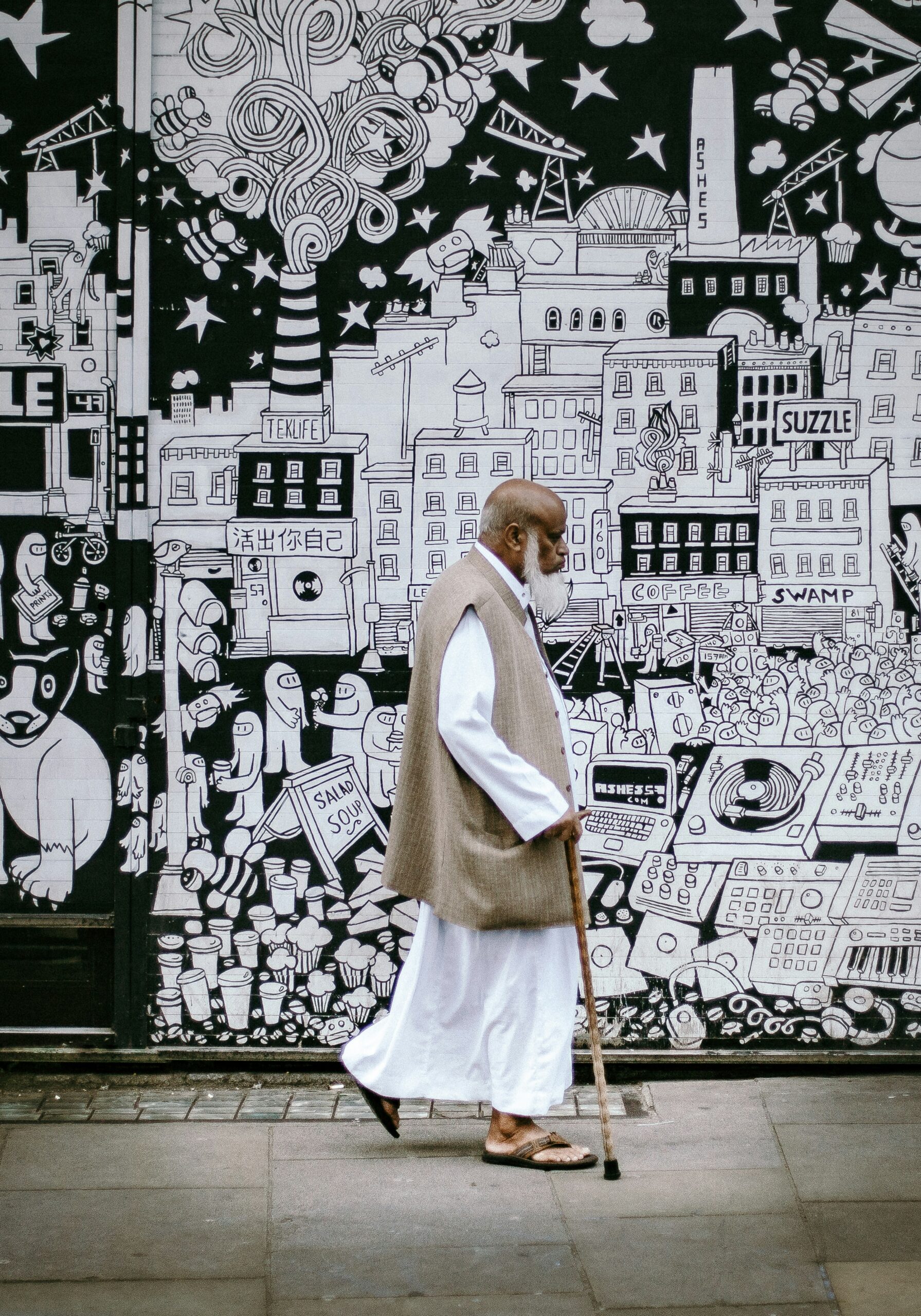Photo of an asian man walking past a mural in London by Clem Onojeghuoon from Unsplash
